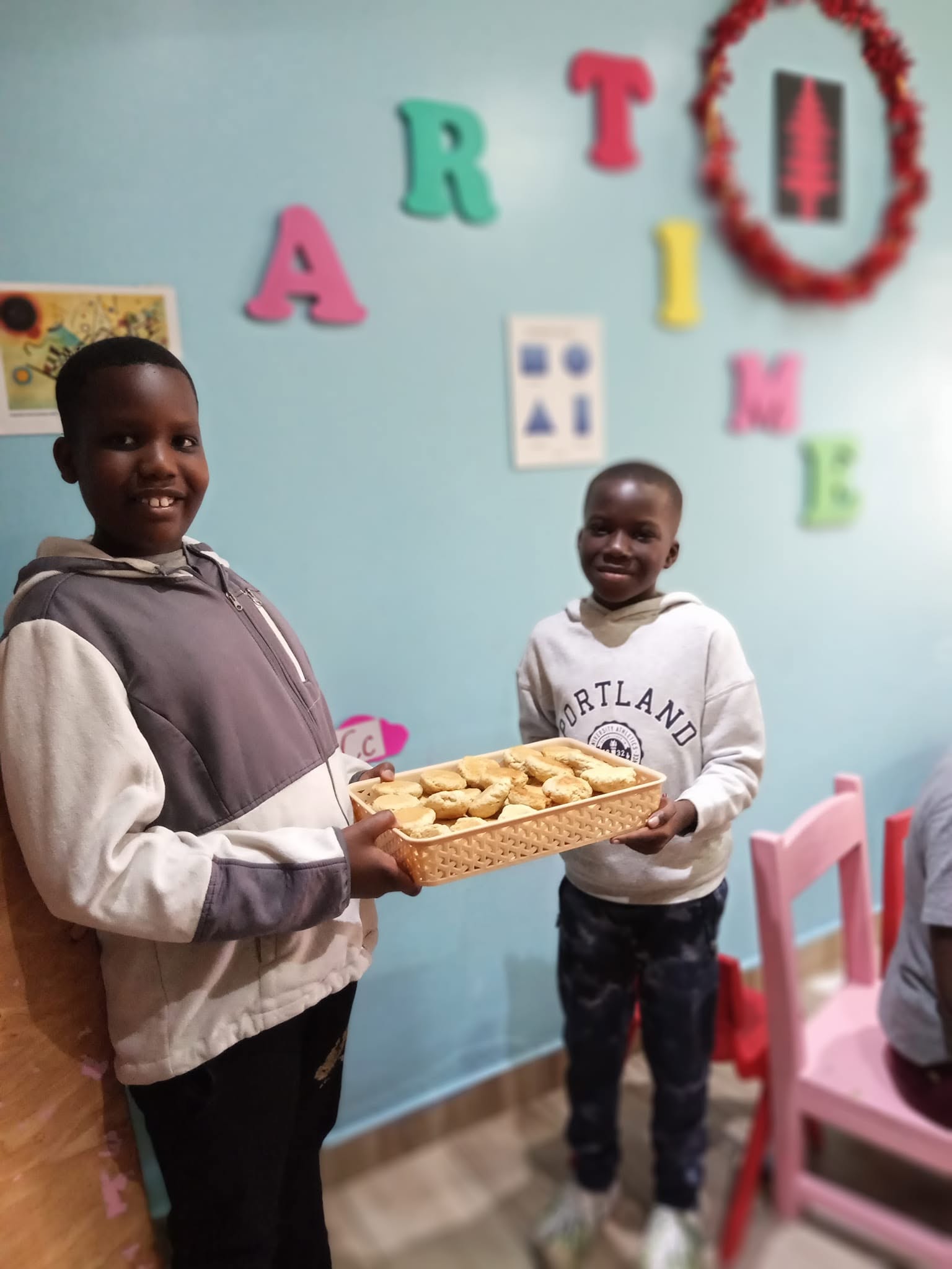 Two boys proudly holding a tray of cookies they baked