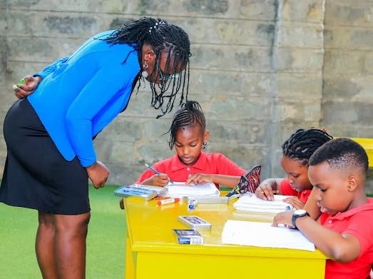 Teacher guiding learners through writing practice at their desk